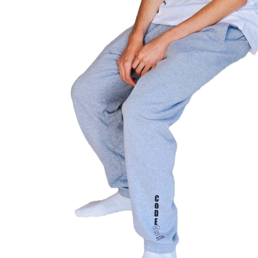 Person wearing grey jogger pants and a white t-shirt on a white background